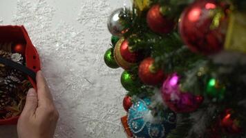 concetto di stagione dei saluti. Impostazione a mano di ornamenti su un albero di natale con luce decorativa foto