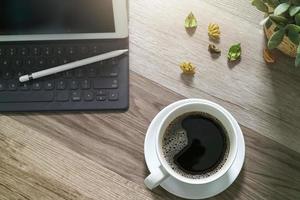 tazza di caffè e tastiera digitale dock da tavolo intelligente, vaso di erbe aromatiche, penna stilo sul tavolo di legno, effetto filtro foto