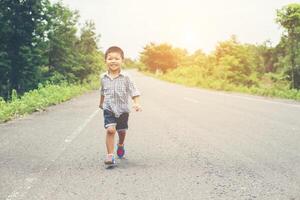 ragazzino felice in movimento, sorridente che corre per strada. foto