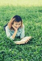 libro di lettura della giovane bella donna hipster nell'erba. foto