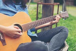 musicista donna e la sua chitarra nel parco naturale, esercitarsi con la chitarra. foto