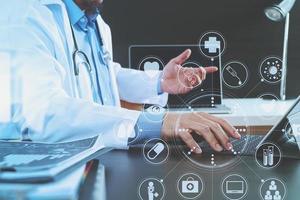 concetto di tecnologia medica. medico che lavora con smartphone e stetoscopio e computer tablet digitale in un ufficio moderno in ospedale foto