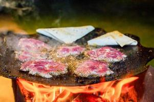 pezzi sottili di carne vengono fritti in una padella sul fuoco con pane pita. cena accanto al fuoco. foto