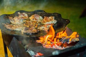 pezzi sottili di carne vengono fritti in una padella sul fuoco. cena accanto al fuoco. foto