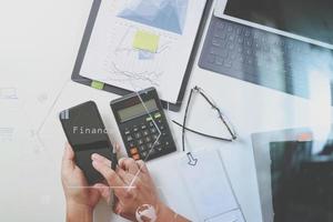 vista dall'alto della mano dell'uomo d'affari che lavora con le finanze su costi e calcolatrice e computer portatile con il telefono cellulare sulla scrivania bianca in un ufficio moderno con diagramma a icone vr foto