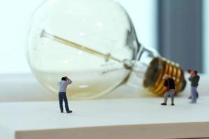 concetto di idea creativa - fotografo in miniatura con lampadina vintage su quaderno di carta aperto foto