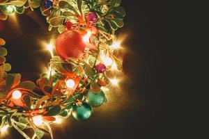 concetto di stagione di auguri. corona di Natale con luce decorativa su sfondo di legno scuro foto