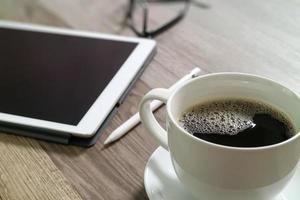 tazza di caffè e tastiera digitale dock da tavolo intelligente, occhiali, penna stilo su tavolo di legno, effetto filtro foto