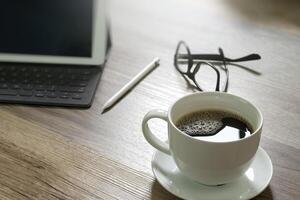 tazza di caffè e tastiera digitale dock da tavolo intelligente, occhiali, penna stilo su tavolo di legno, effetto filtro foto