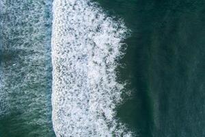 Visualizza di un' onda su il riva di un' spiaggia a Alba, e persone fare surf. aereo superiore Visualizza fotografia con un' drone. foto