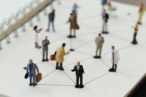 primo piano di persone in miniatura con diagramma di rete sociale su notebook aperto su scrivania in legno come concetto di social media foto