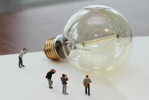 concetto di idea creativa - fotografo in miniatura con lampadina vintage su quaderno di carta aperto foto