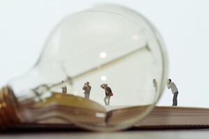 concetto di idea creativa - fotografo in miniatura con lampadina vintage su quaderno di carta aperto foto