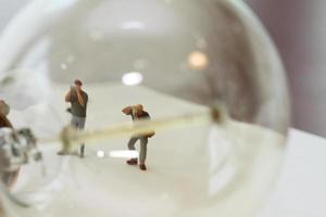 concetto di idea creativa - fotografo in miniatura con lampadina vintage su quaderno di carta aperto foto