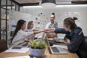 gruppo di colleghi multirazziali lavoro di squadra di brainstorming e solidarietà unendo le mani insieme alla leader donna caucasica per il potere e il successo sindacale dell'azienda in una sala riunioni di un ufficio commerciale. foto