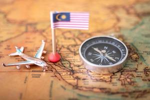 la bandiera della malesia, l'aereo e la bussola sulla mappa del mondo. foto