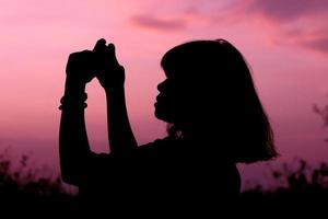 silhouette colpo medio di donna o donna in piedi con lo sfondo del tramonto del cielo sull'ora del tramonto. foto