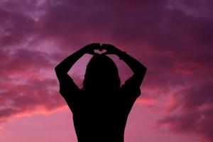 silhouette colpo medio di donna o donna in piedi con lo sfondo del tramonto del cielo sull'ora del tramonto. foto