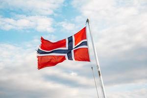 bandiera della Norvegia su uno sfondo di cielo blu con nuvole foto