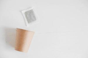 tazza di carta e bustina di tè quadrata asciutta su sfondo bianco. vista dall'alto. copia, spazio vuoto per il testo foto