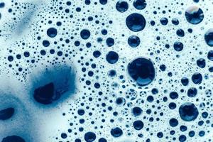 bolle di sapone su uno sfondo di acqua blu come texture. vista dall'alto. copia, spazio vuoto per il testo foto