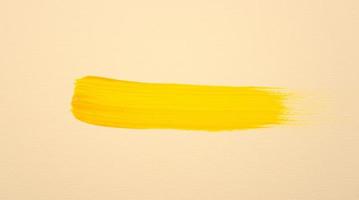 colore acrilico oro giallo brillante con pennellata disegnata a mano su sfondo color terra pastello. trama artistica fluida su tela. foto