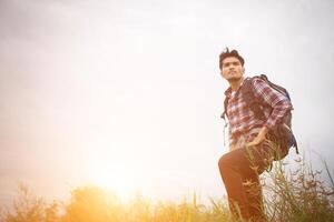 ritratto di giovane uomo hipster all'aperto alzando le mani con lo zaino sulla spalla, turismo d'avventura. foto