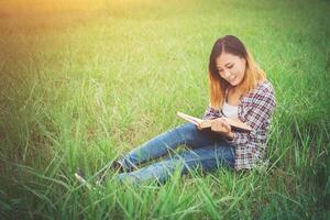 libro di lettura seduto giovane bella hipster sul pascolo. foto