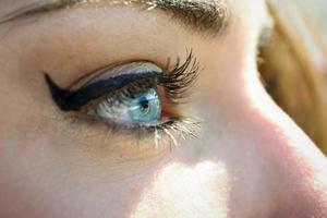 primo piano degli occhi azzurri della giovane donna con le ciglia lunghe foto