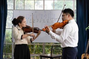 studente che impara a suonare il violino con l'insegnante in classe foto