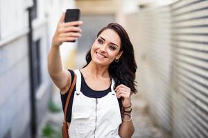 ragazza che cattura la fotografia del selfie con lo smartphone all'aperto foto