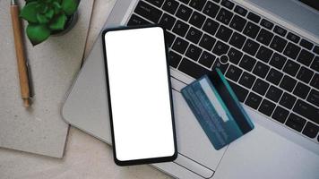 modello di mockup di telefono cellulare con schermo bianco su un laptop per il lavoro a distanza e il concetto di home office foto