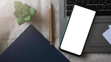 modello di mockup di telefono cellulare con schermo bianco su un laptop per il lavoro a distanza e il concetto di home office foto