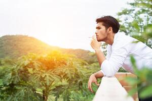 giovane uomo hipster che si riposa, fuma sigaretta con la natura e la brezza fresca. foto