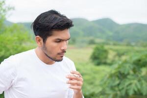 giovane uomo hipster che si riposa, fuma sigaretta con la natura e la brezza fresca. foto