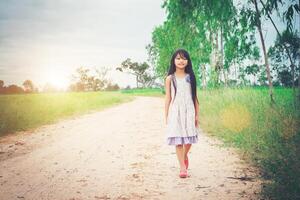 la bambina con i capelli lunghi che indossa un vestito si sta allontanando da te lungo una strada rurale. foto