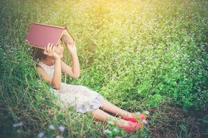 piccolo libro di copertina carino ragazza asiatica sulla sua testa alla natura. foto