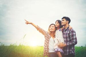 famiglia di madre, padre e figlio sul prato, papà che porta la figlia. foto