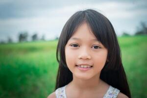 primo piano di dolce bambina all'aperto con sorridente nel campo estivo. foto