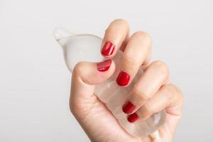preservativo asiatico della tenuta della mano della donna su fondo bianco foto