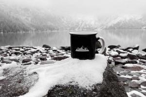 coppa per l'iscrizione. tazza nera sullo sfondo di un lago di montagna in inverno foto