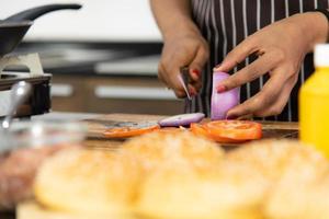 le giovani donne africane si nutrono a vicenda e sorridono mentre cucinano l'insalata in cucina foto