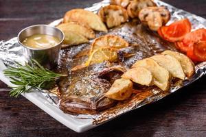 gustoso pesce fritto con patate e pomodori su un piatto rettangolare bianco foto