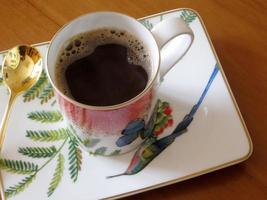 tazza da caffè di bellezza in piedi sul tavolo di legno con caffè scuro e gustoso foto