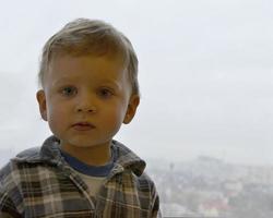 bellissimo bambino con la faccia da bambino in posa fotografo vicino alla finestra foto