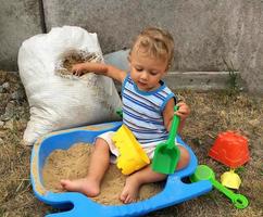 bellissimo bambino in una buca di sabbia per bambini in posa fotografo vicino a sandbox foto