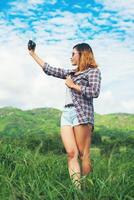 giovane donna hipster con fotocamera retrò che cattura il paesaggio all'aperto, la natura della montagna di stile di vita sullo sfondo. foto