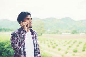 giovane uomo barbuto hipster che parla al telefono, sorridente, vista montagna esterna. foto