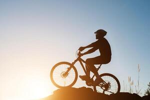 sagoma di un uomo in mountain bike durante il tramonto. foto