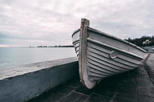 vecchia barca bianca in legno su un molo di cemento al tramonto foto